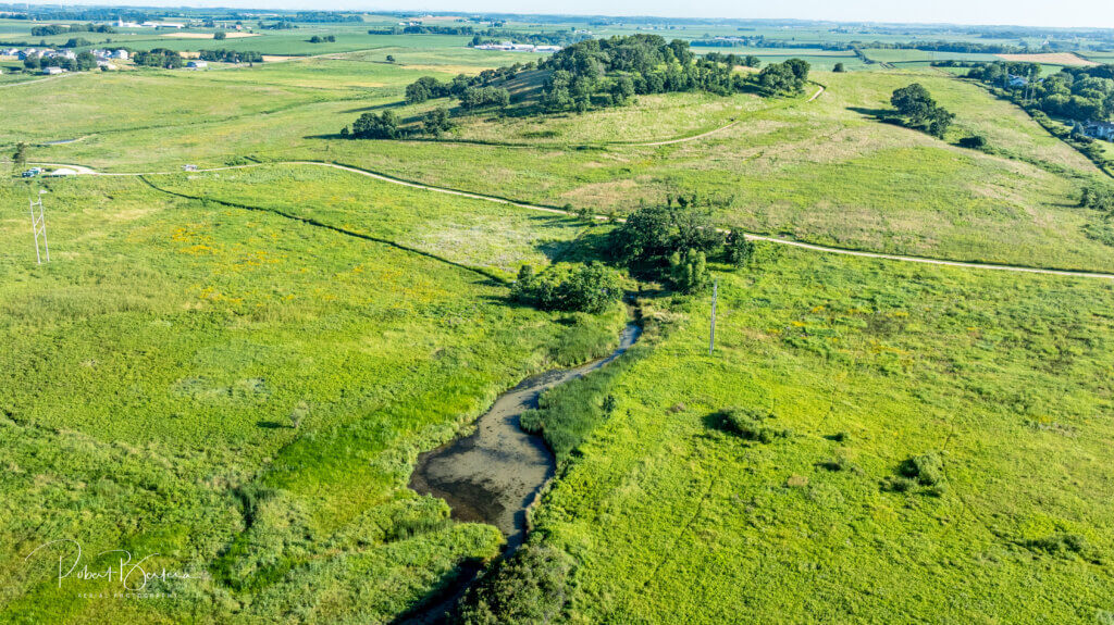 View of Frederick's Hill in the background at Pheasant Branch Conservancy, with Frederick's Spring near the grouping of trees in the center of the photo. Pheasant Branch Creek extends toward the bottom of the photo from the spring. Photo courtesy Robert Bertera.