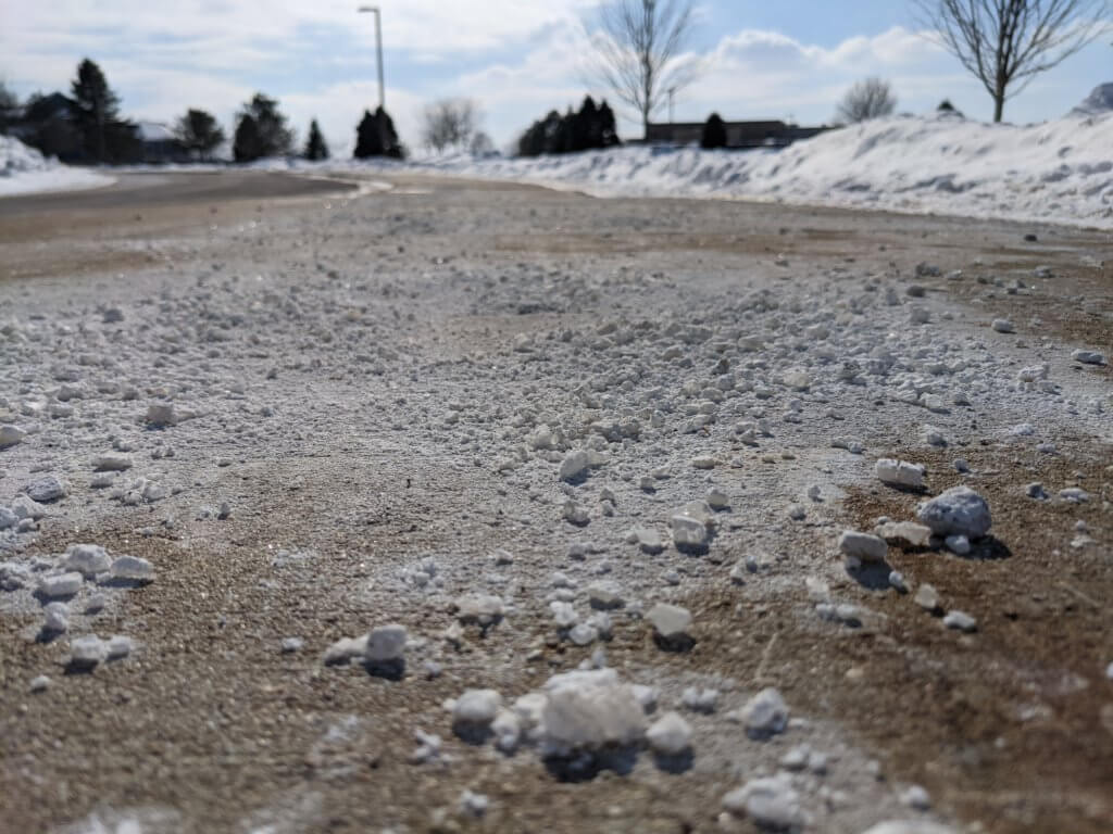Leftover salt on a sidewalk at the end of the winter season - sweep up leftover salt for healthy lakes